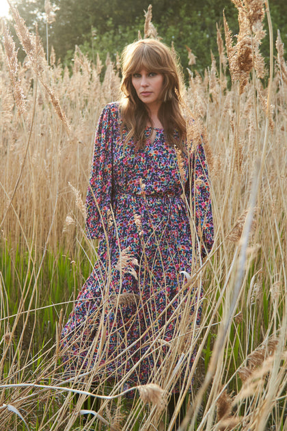 A sustainable woman in a Miniature Floral Garden Dress standing amidst tall grass.