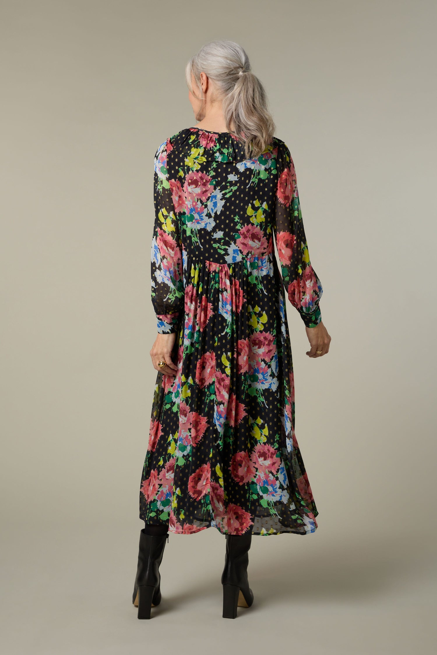 The back view of an older woman wearing a Floral Bouquet Frill Dress with a free-flowing fit.