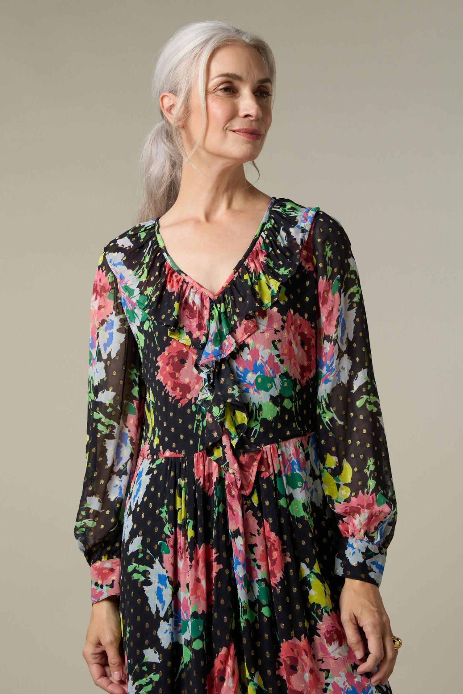A woman wearing a Floral Bouquet Frill Dress, with a print of flowers. The Floral Bouquet Frill Dress has a print of flowers.