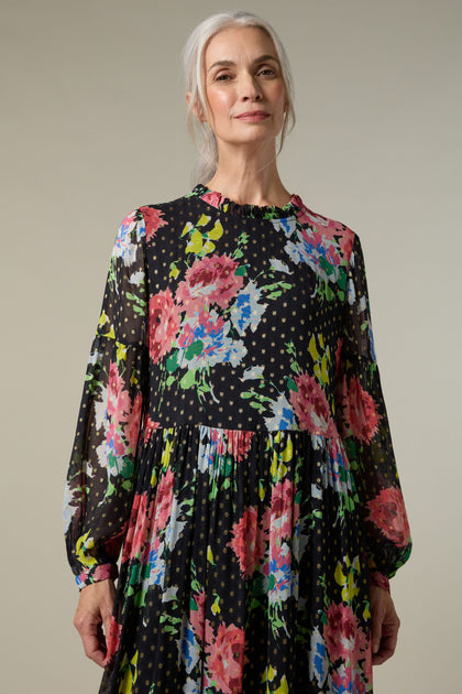 A woman wearing a Floral Bouquet Maxi Dress, showcasing a print of flowers and polka dots on layered viscose. The Floral Bouquet Maxi Dress features a print of flowers and polka dots on layered viscose.