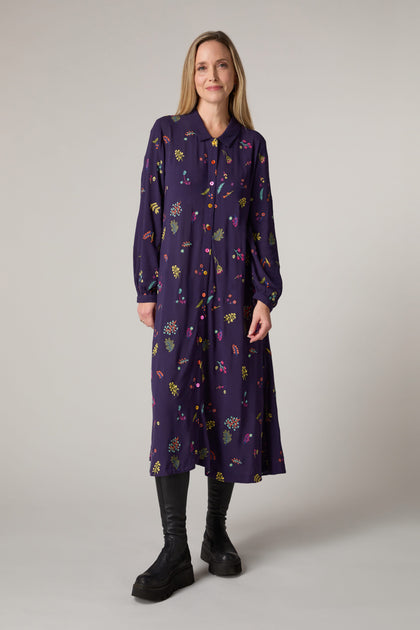 A woman wearing a Winter Sprig Crepe shirt dress with delicate embroidery detailing.
