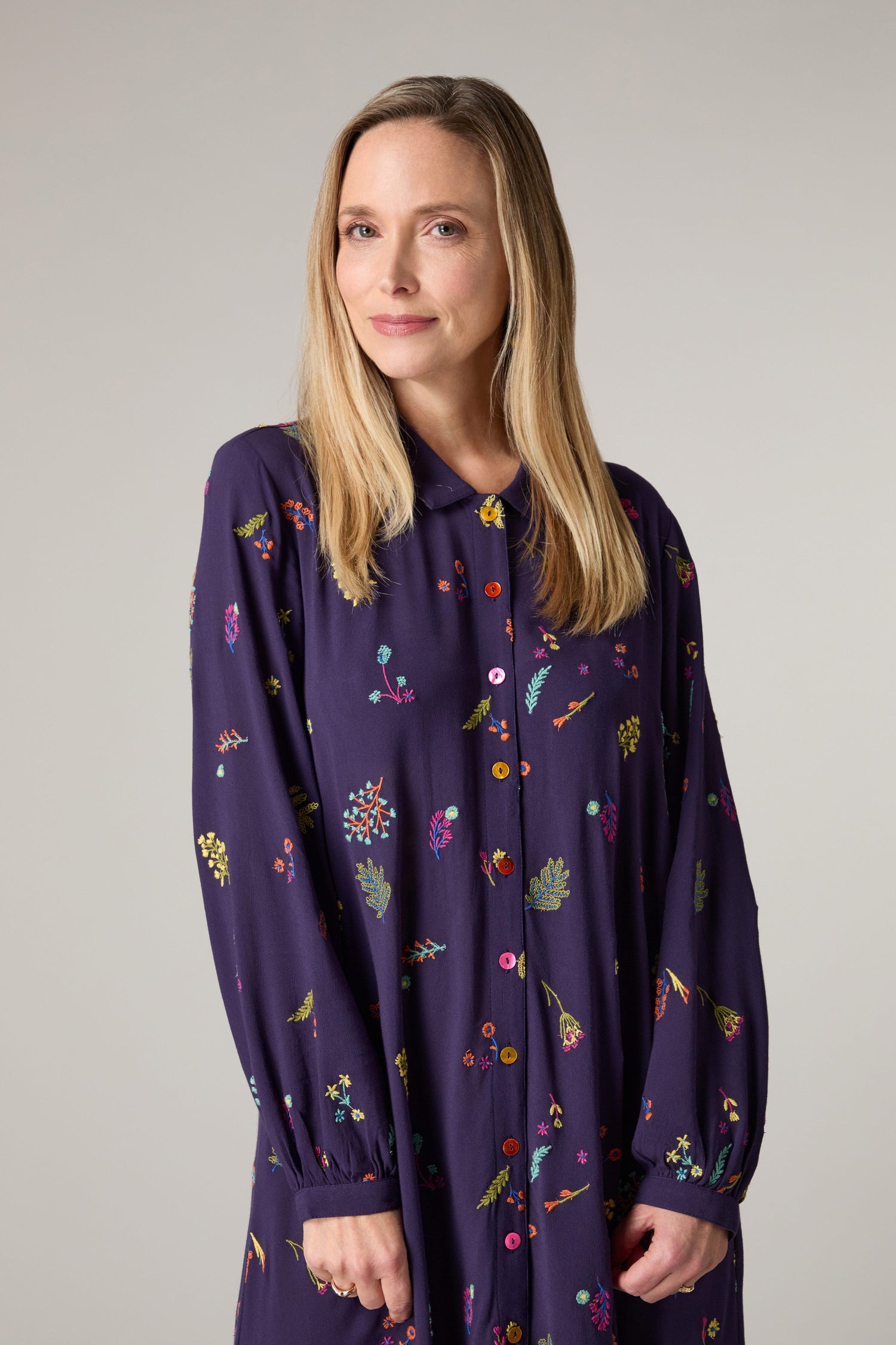 A woman wearing a Winter Sprig Crepe Shirt Dress adorned with delicate floral embroidery.