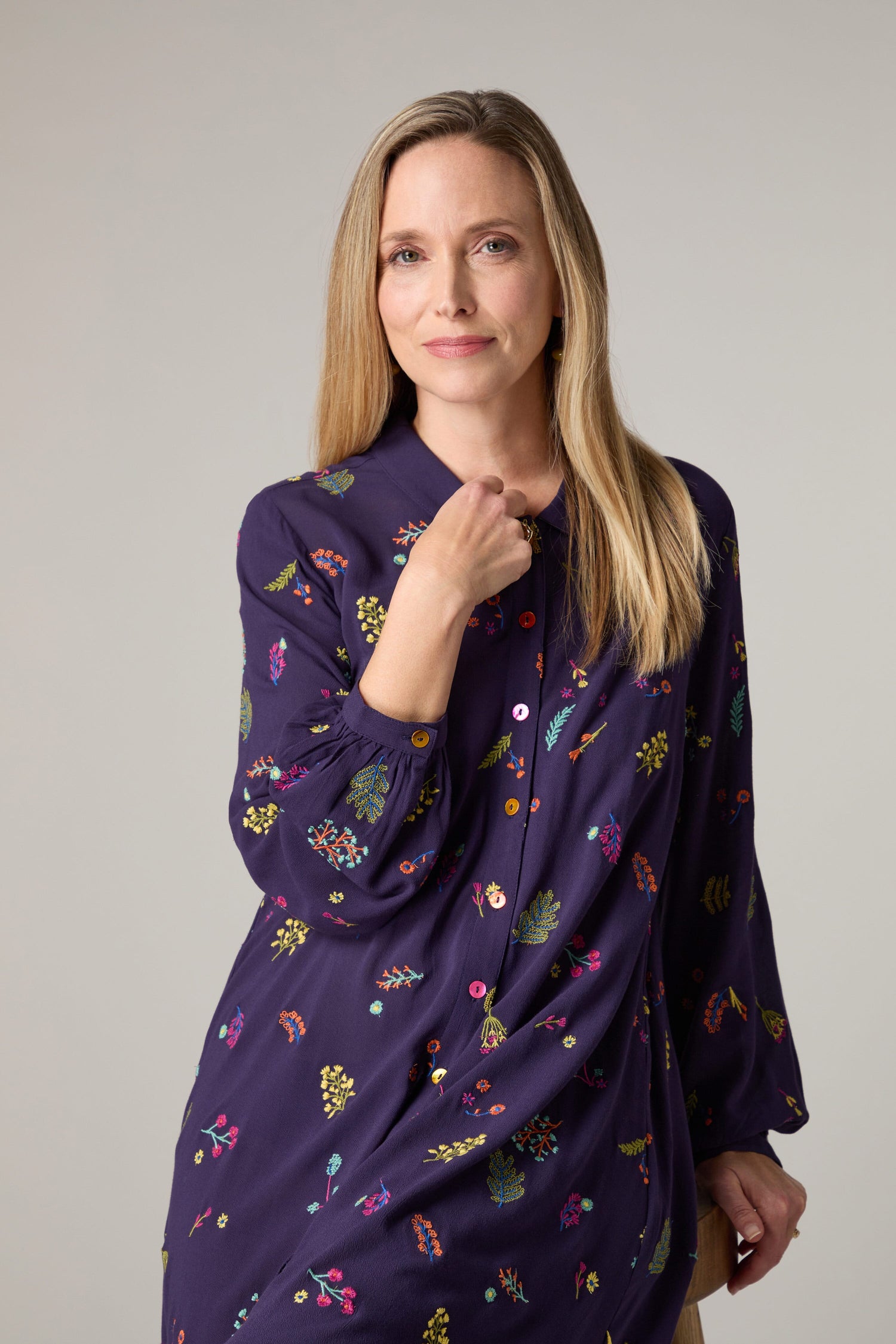 A woman is posing for a photo in an exquisite Winter Sprig Crepe Shirt Dress with intricate embroidery.