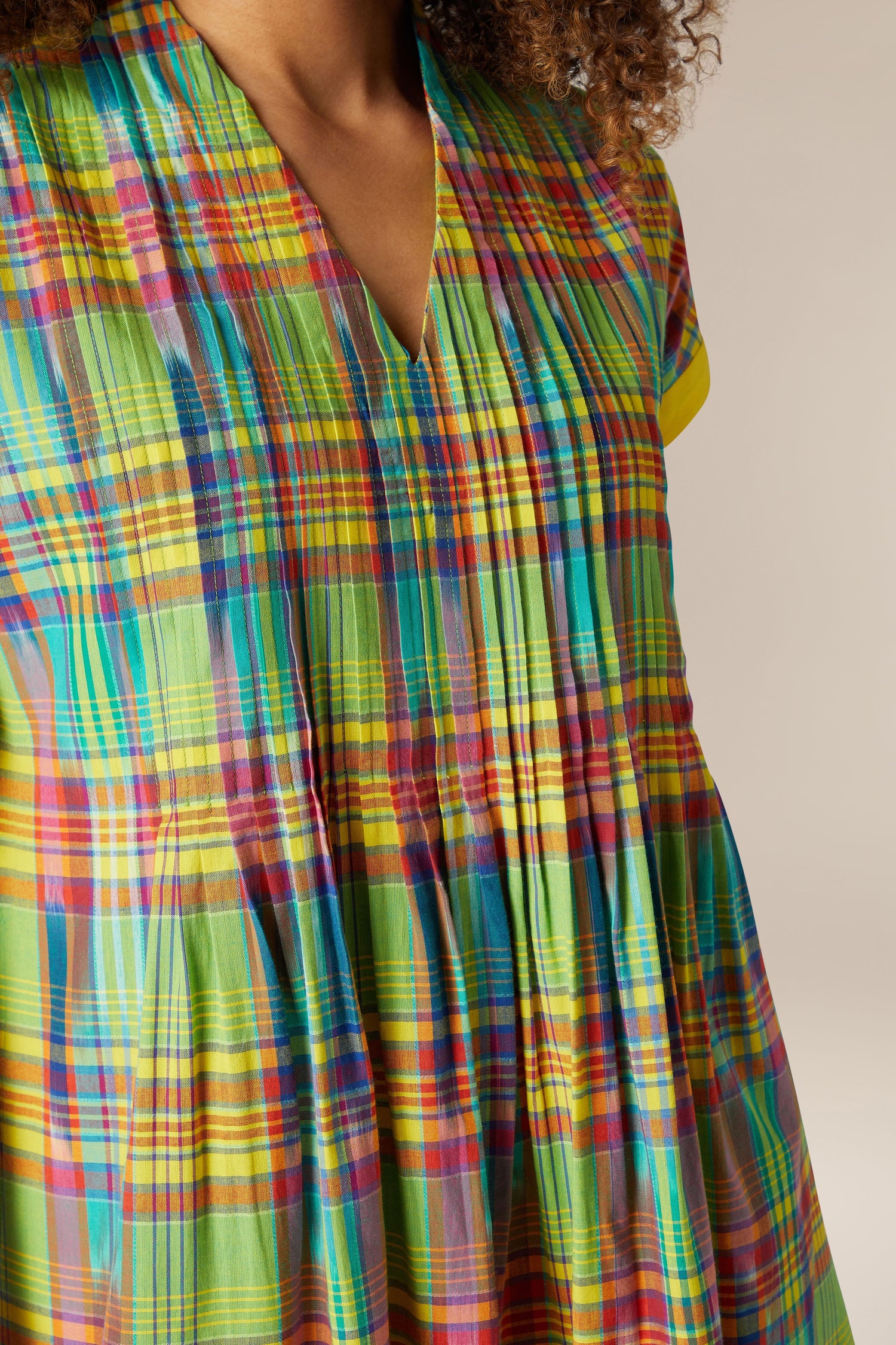 Close-up of a woman wearing a vibrant, Multicoloured Ikat Check Dress with a focus on the fabric and design details.