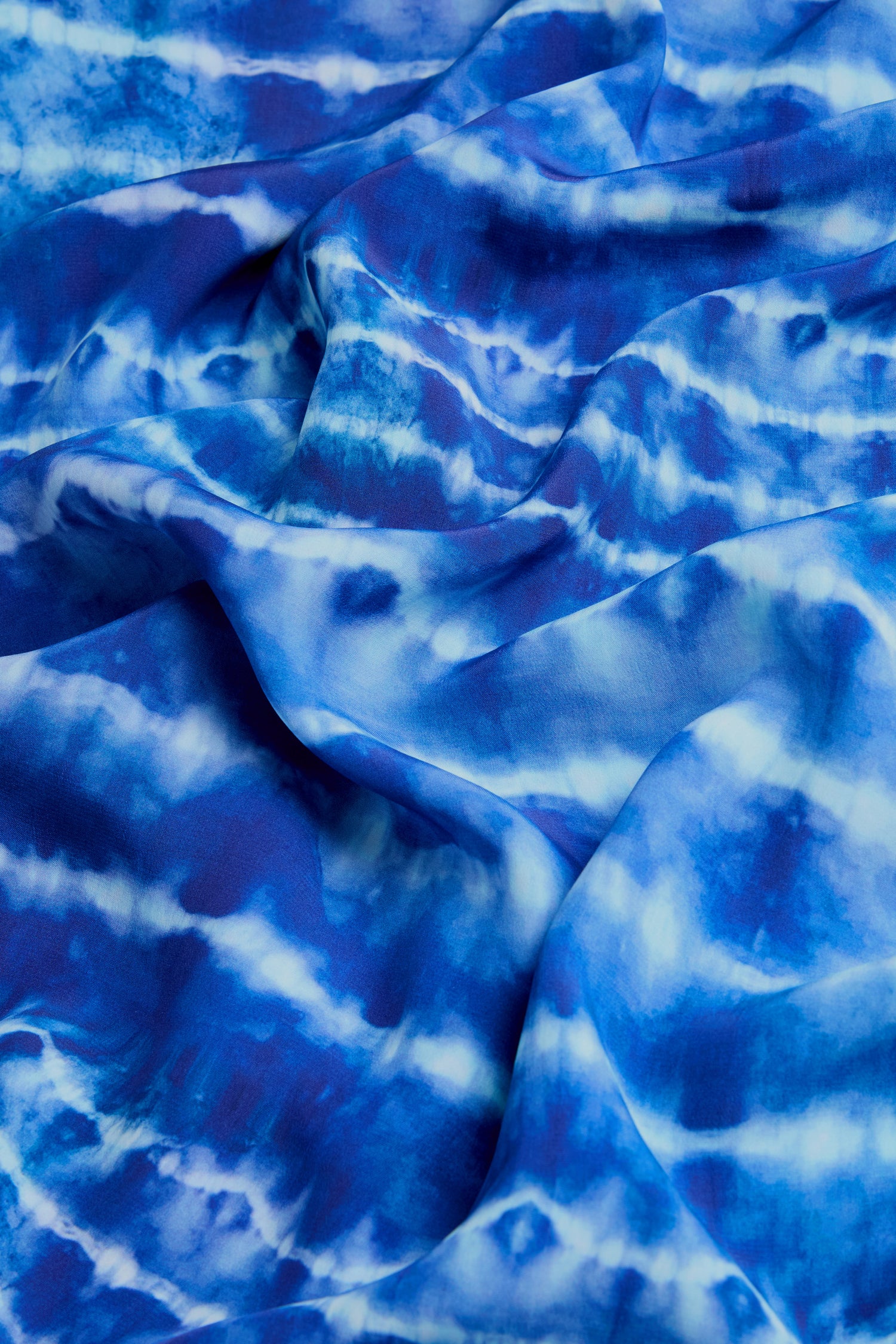 The Tie Dye Printed Viscose Pleated Dress features a blue and white wavy, marbled pattern—ideal for a chic, flowy look.