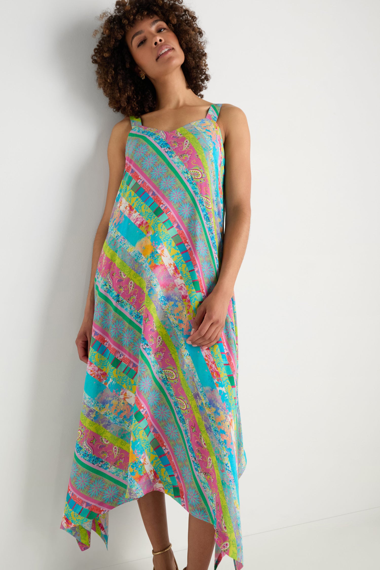 A woman models the Patchwork Stripe Summer Dress, a colorful, sleeveless dress made from soft viscose crepe, shown against a white background—ideal for summer.