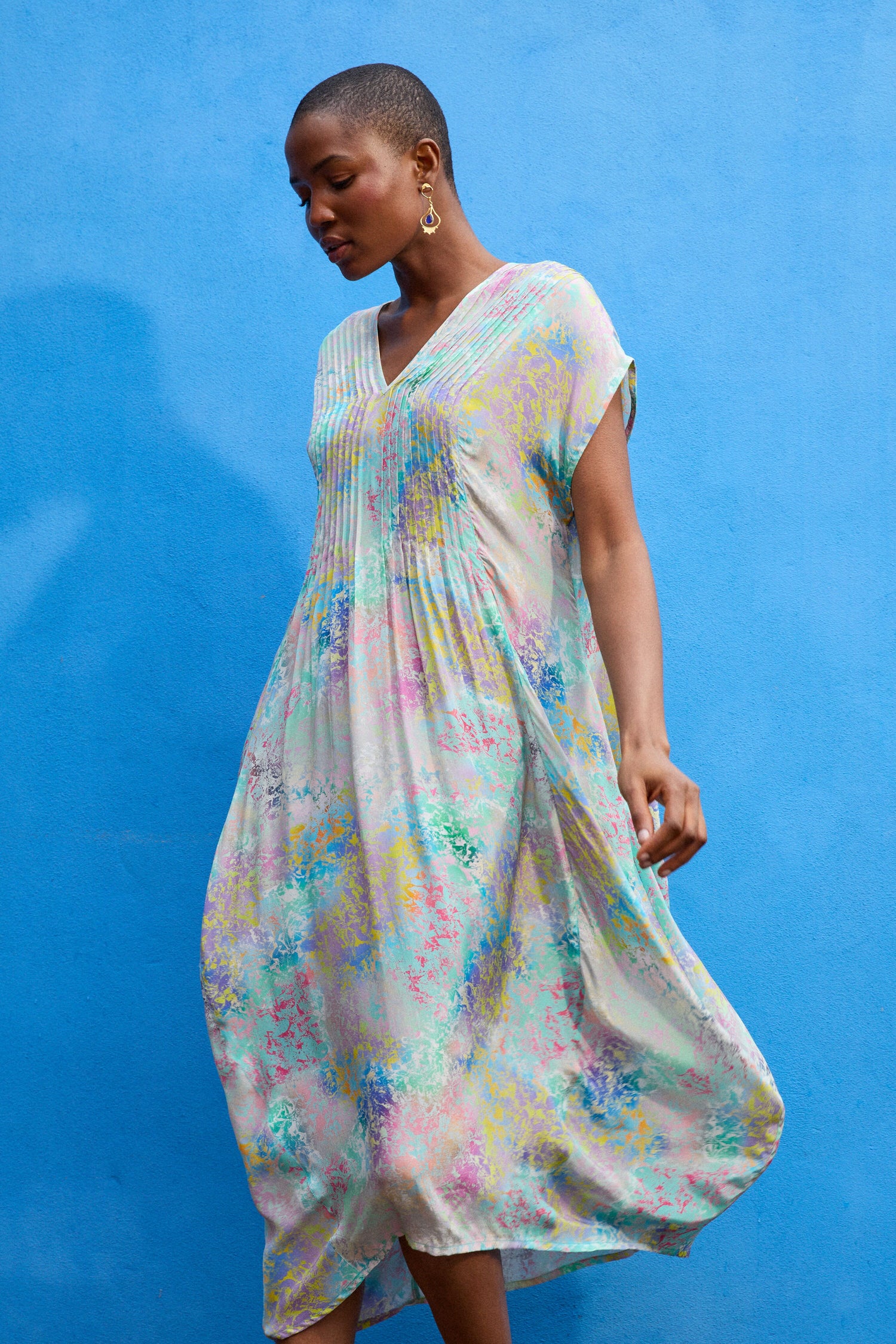 A person wearing a Marbled Cloud Print Bubble Dress stands against a bright blue wall, looking down and slightly to the side.