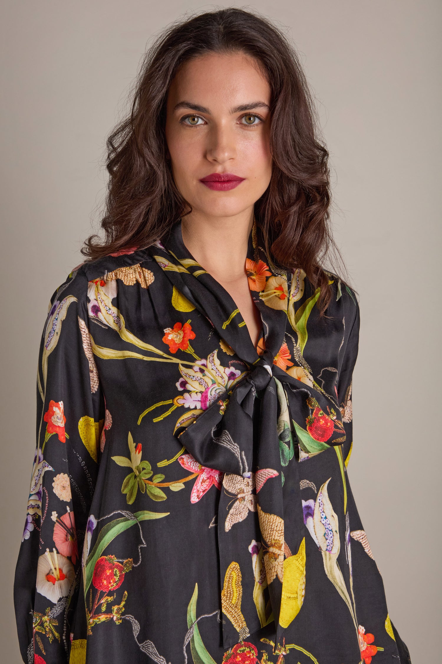 The woman stands against a plain background, wearing the Vintage Floral Tie Front Dress, which features an elegant bow at the neck.