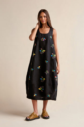 A woman stands against a neutral background wearing the Vintage Floral Embroidered Bubble Dress with colorful embroidery and brown sandals.