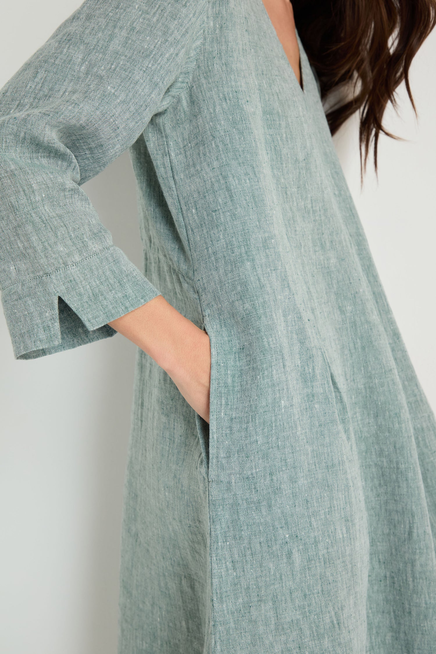 A person wearing the Crinkle Linen Cross Dye Bubble Dress in light teal, featuring a loose fit, three-quarter sleeves, bubble silhouette, and side pocket.