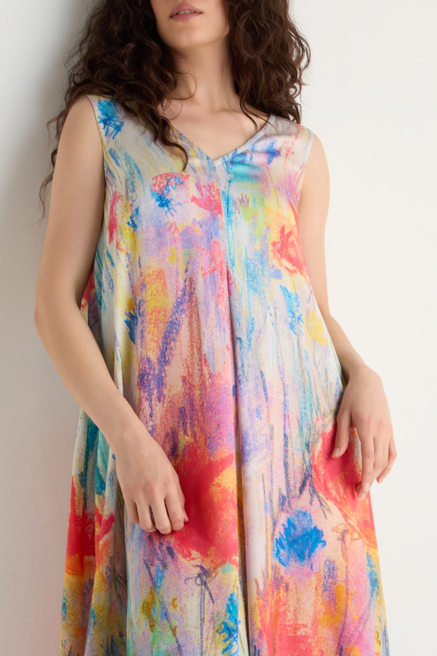 A woman models the Meadow Dreams Sleeveless Dress with an A-line silhouette and wildflower print, standing against a plain white background.