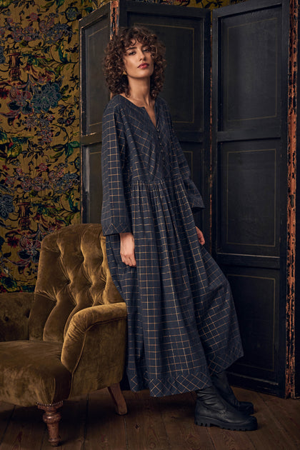 A person wearing a charcoal gray Lurex Check Flared Dress, featuring a subtle grid pattern and a long-sleeved, flared skirt.