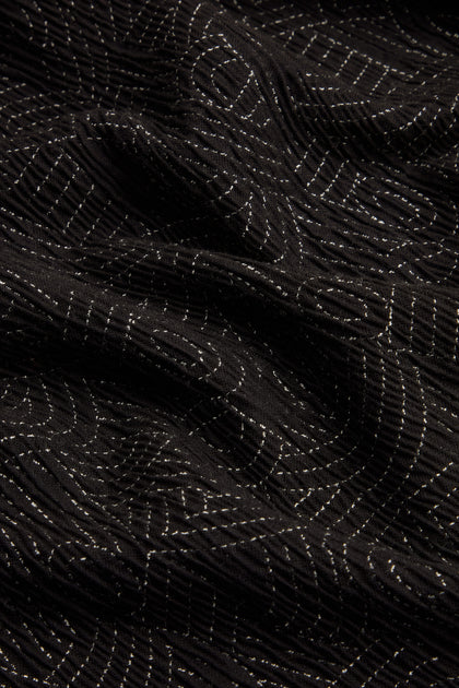 Close-up of black fabric with undulating folds, featuring thin, white, horizontal and curved stitched lines that echo the intricate detailing of the Stitched Jacquard Jacket.