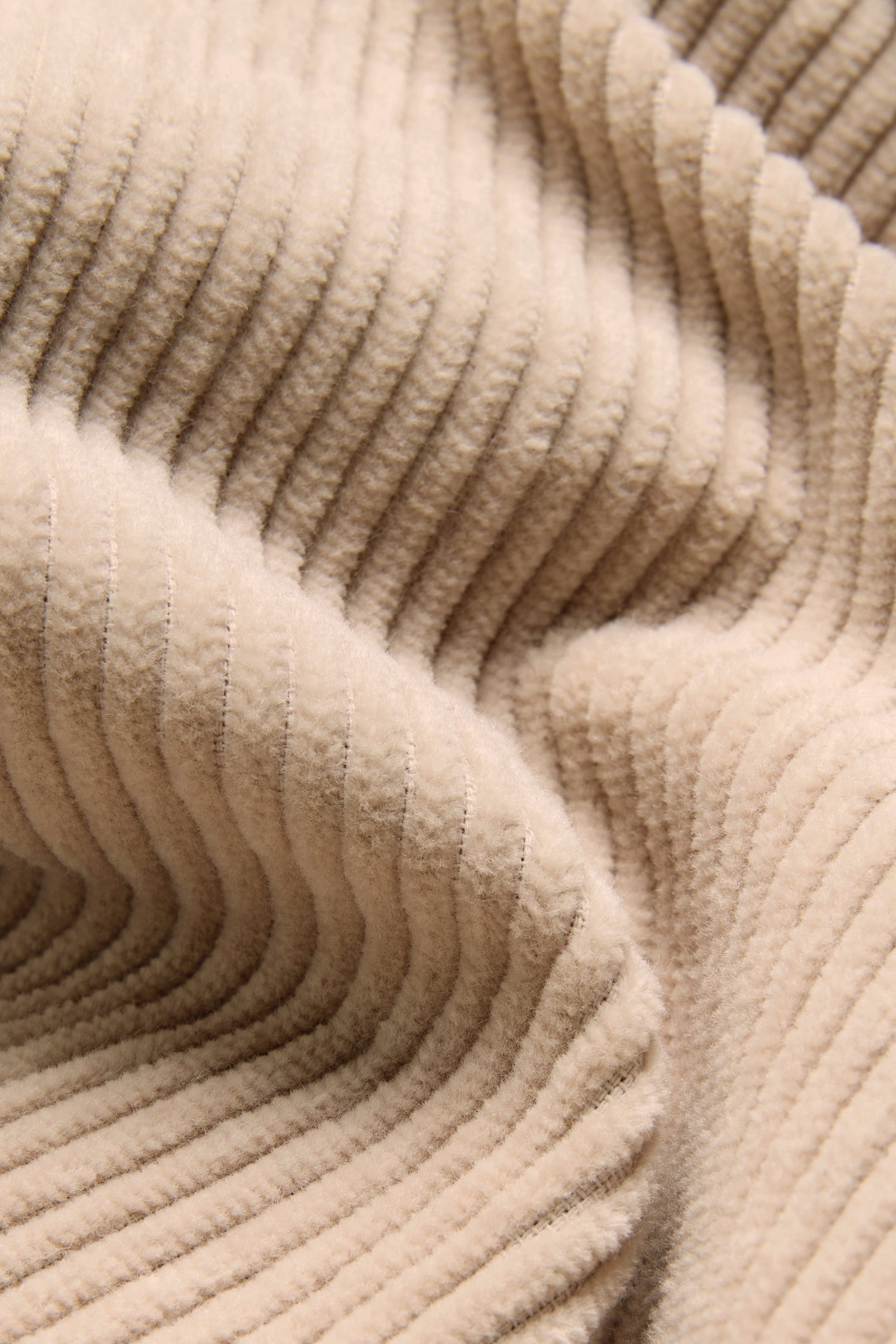 Close-up of beige corduroy fabric, crafted from pure cotton, showing soft ridges and folds—perfect for the Ecru Jumbo Cord Caban Jacket.