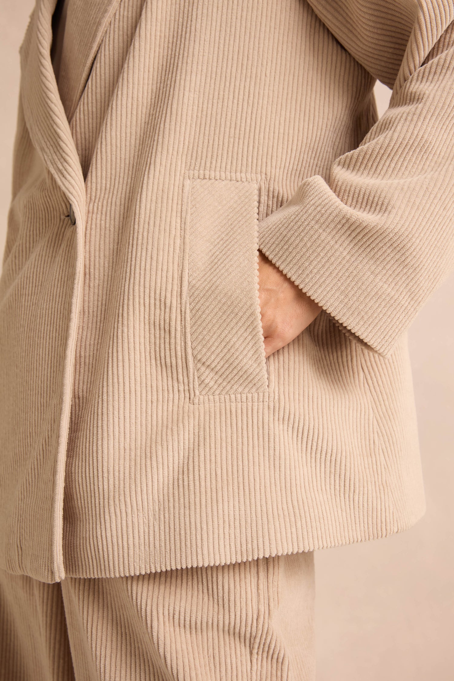 A person wearing an Ecru Jumbo Cord Caban Jacket with one hand placed inside a front pocket.
