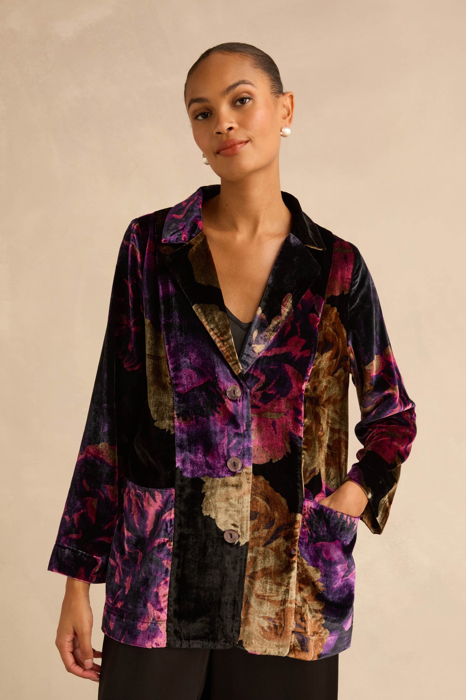 A person wears a Midnight Peonies Velvet Relaxed Blazer featuring a relaxed fit and a purple and gold floral print.