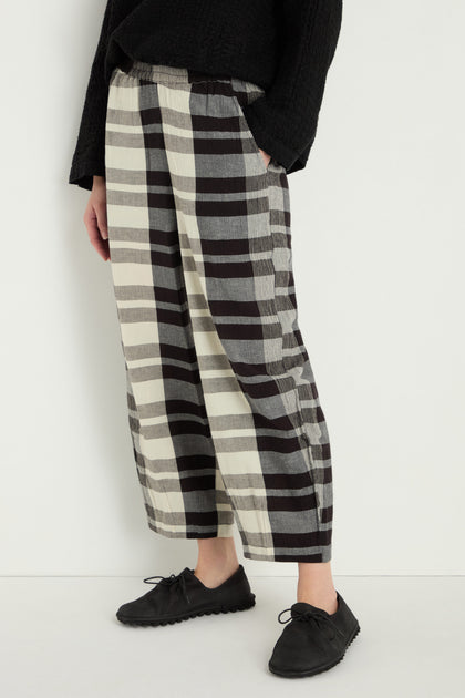 Person wearing Monochrome Crinkle Check Bubble Trouser—wide-leg, cropped style—with hands in pockets, a black textured top, and black lace-up shoes, standing against a plain white background.