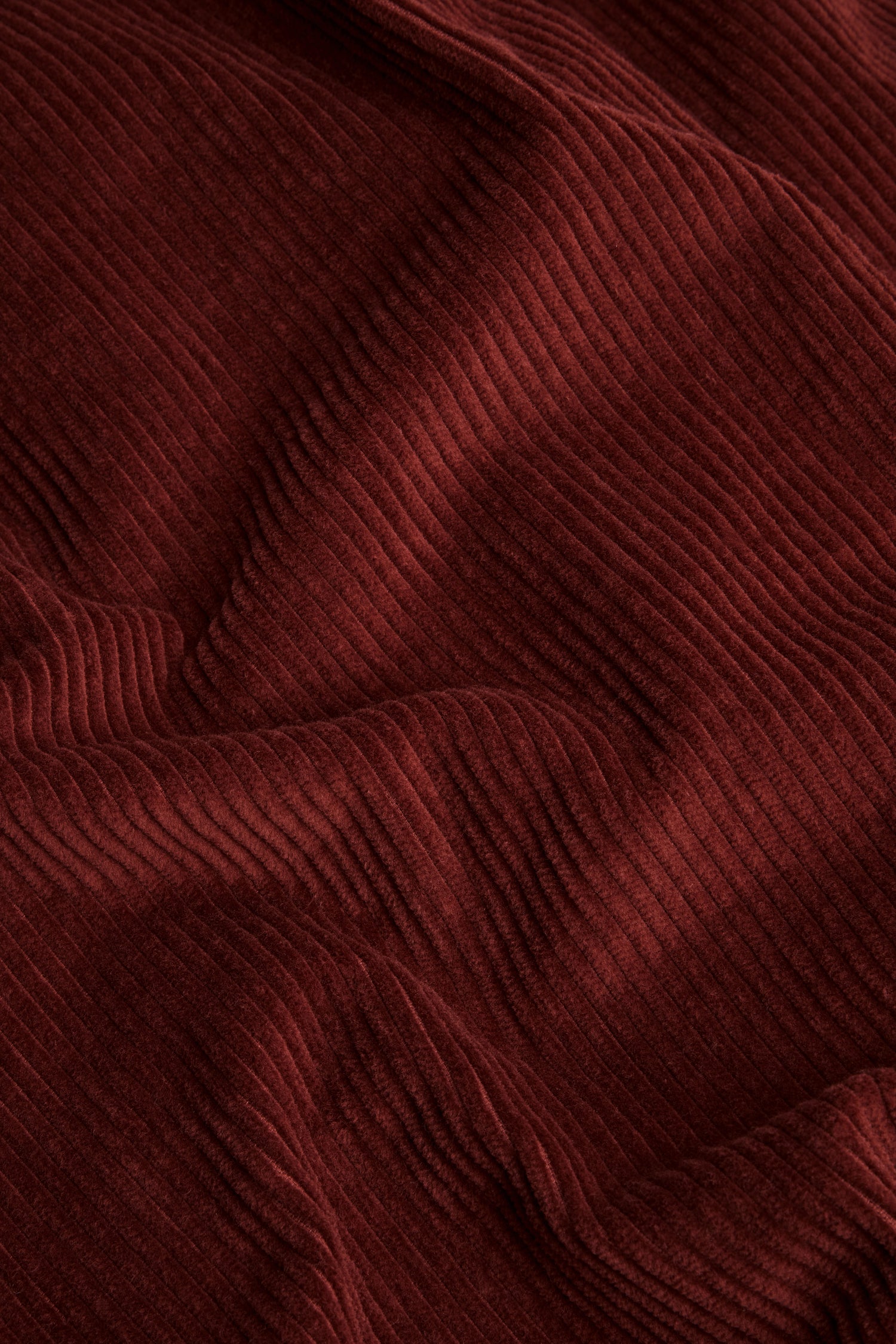 Close-up of Conker Jumbo Cord Bubble Trouser in reddish-brown, highlighting the textured vertical ridges and soft folds of its cotton corduroy fabric, characteristic of the pull-on style with a relaxed bubble silhouette.