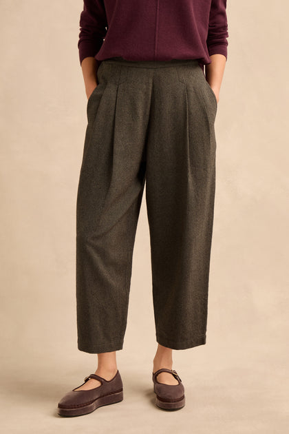 A person wearing a burgundy long-sleeve top, the Overdyed Twill Barrel Trouser in gray, and maroon Mary Jane shoes stands against a neutral background with hands in their pockets.