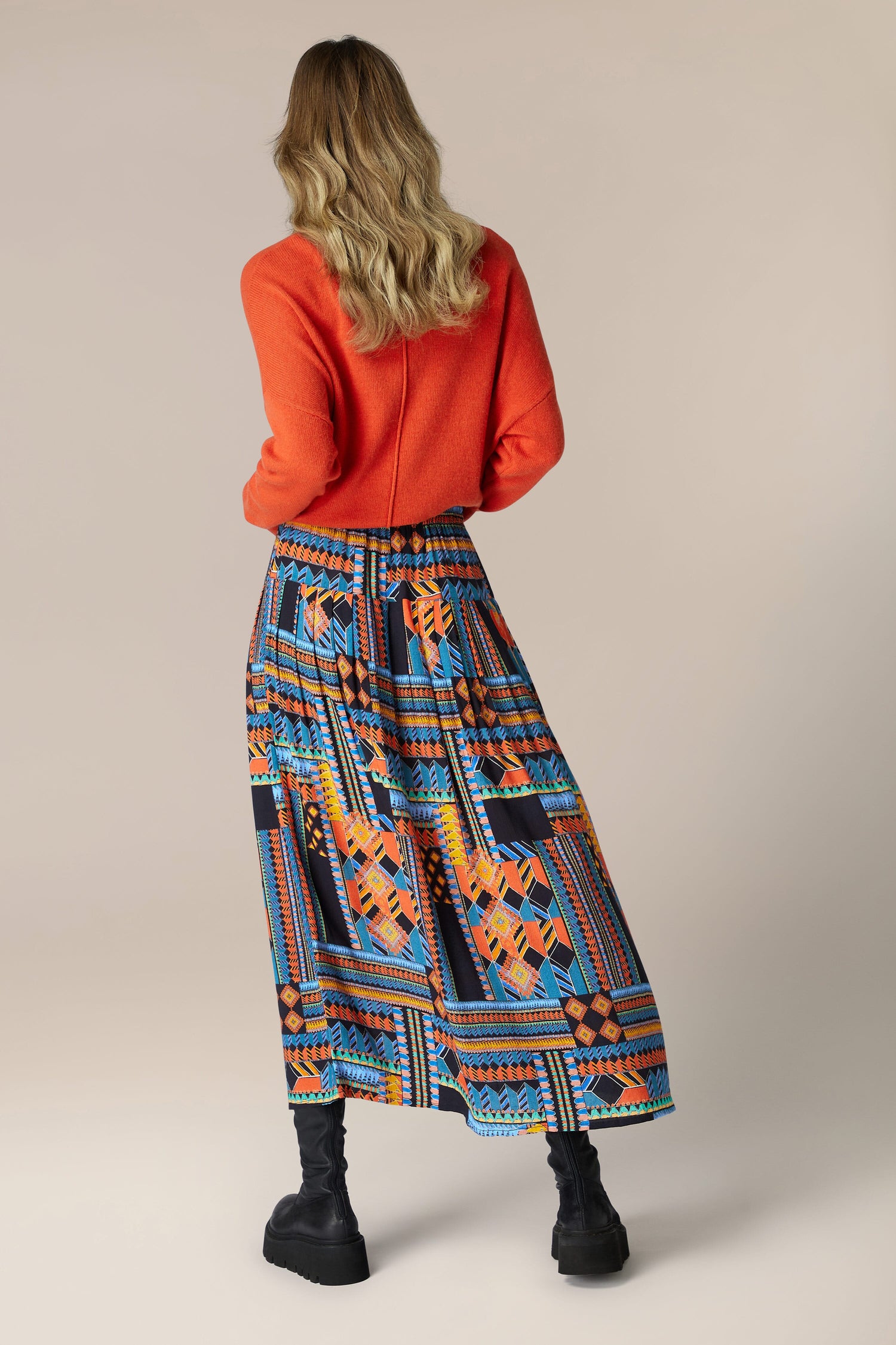 The back view of a woman wearing a flowing midi length, Bold Graphic printed skirt.