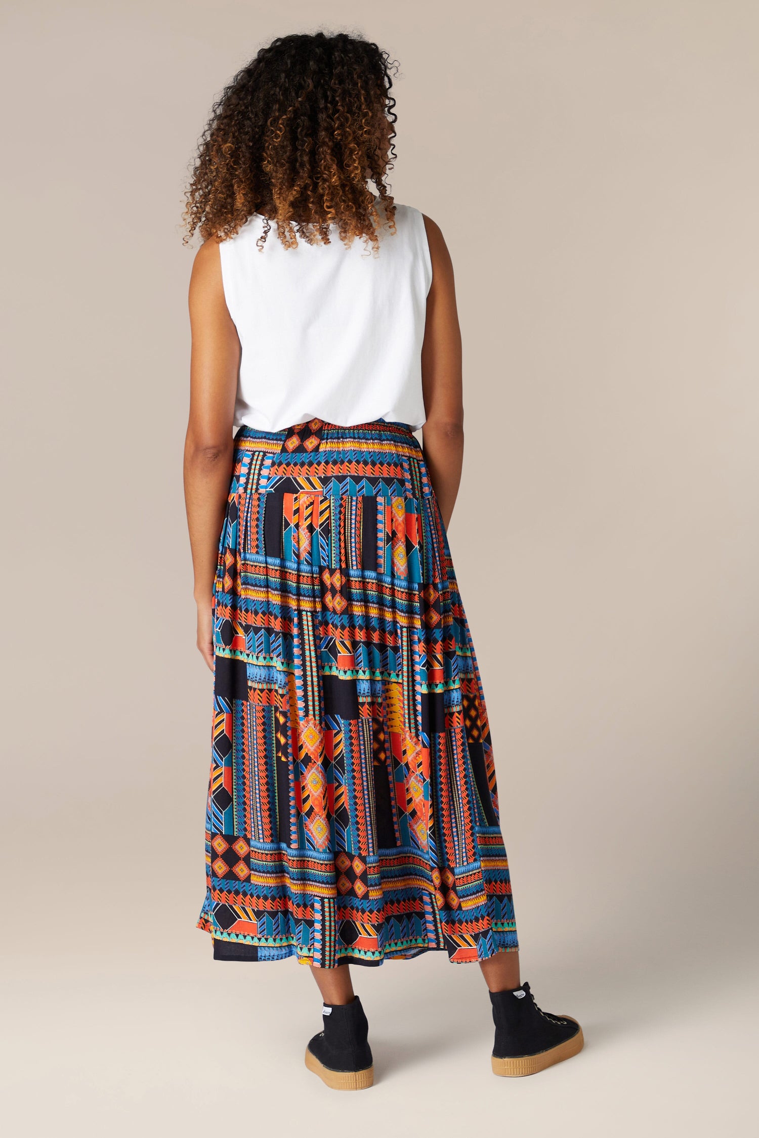 The back view of a woman wearing a flowing midi length Bold Graphic Printed Skirt