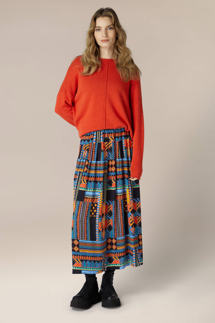 A woman wearing a Bold Graphic Printed Skirt, flowing midi length.