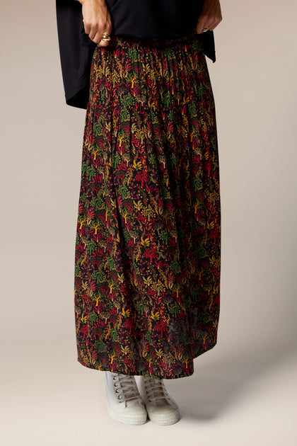 A woman wearing a black shirt and a Magical Forest Print Skirt.