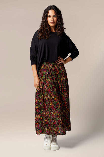 A woman wearing a Magical Forest Print Skirt with autumnal tones.