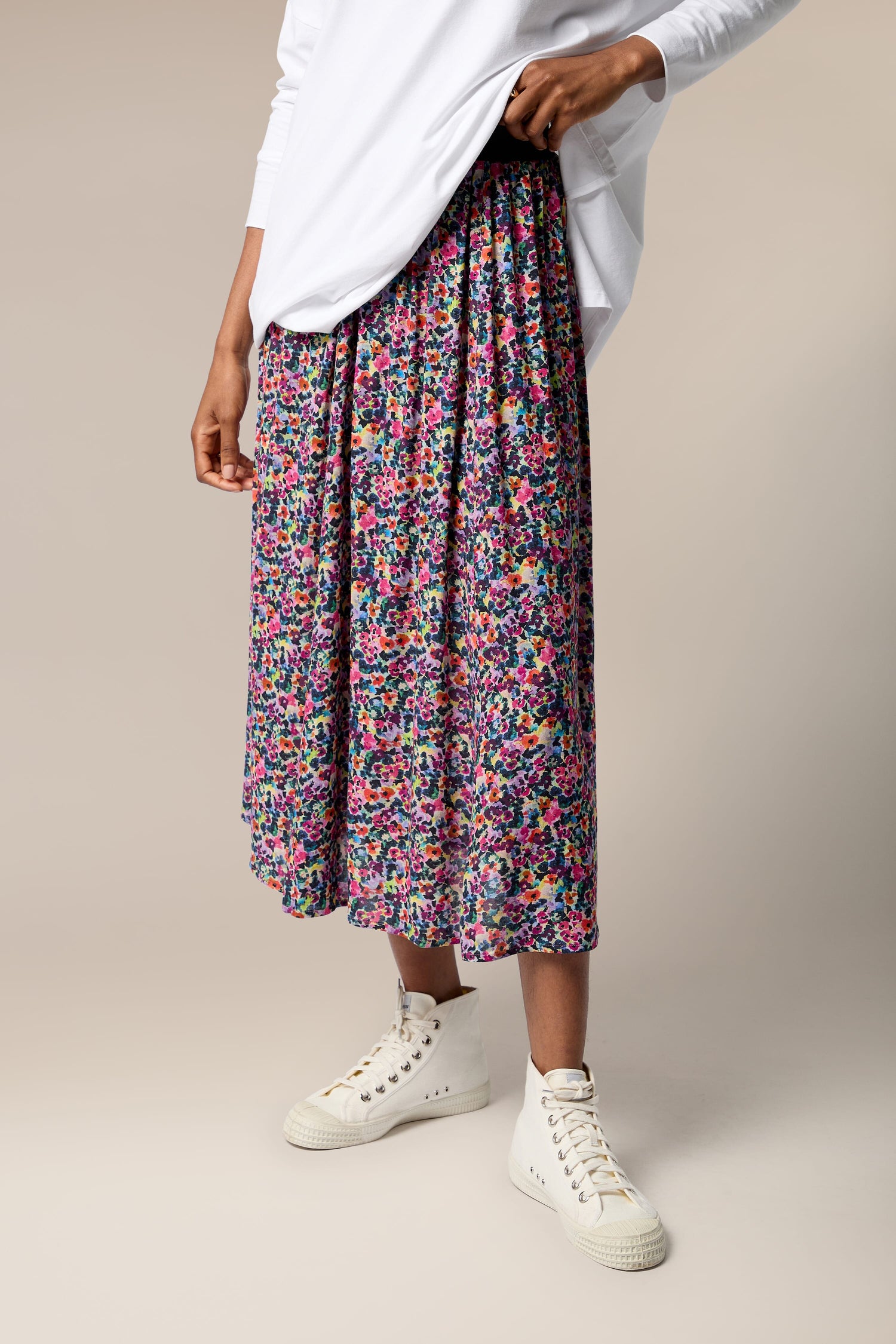 A woman wearing a Miniature Floral Garden Skirt with a white t-shirt.