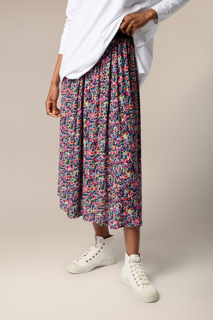 A woman wearing a Miniature Floral Garden Skirt with a white t-shirt.