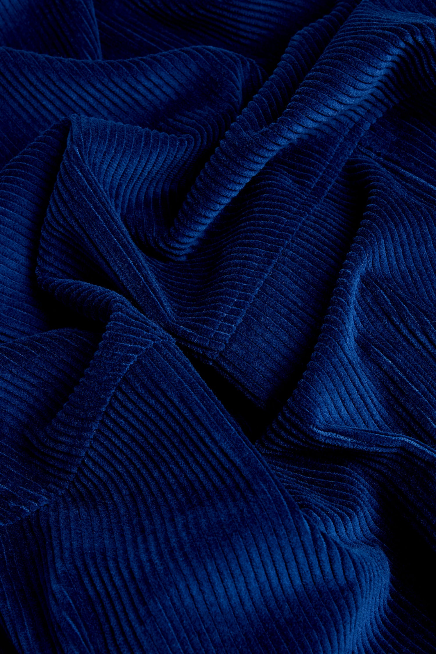 Close-up of deep blue corduroy fabric with pronounced ridges and folds, characteristic of the Jumbo Cord Bubble Skirt.