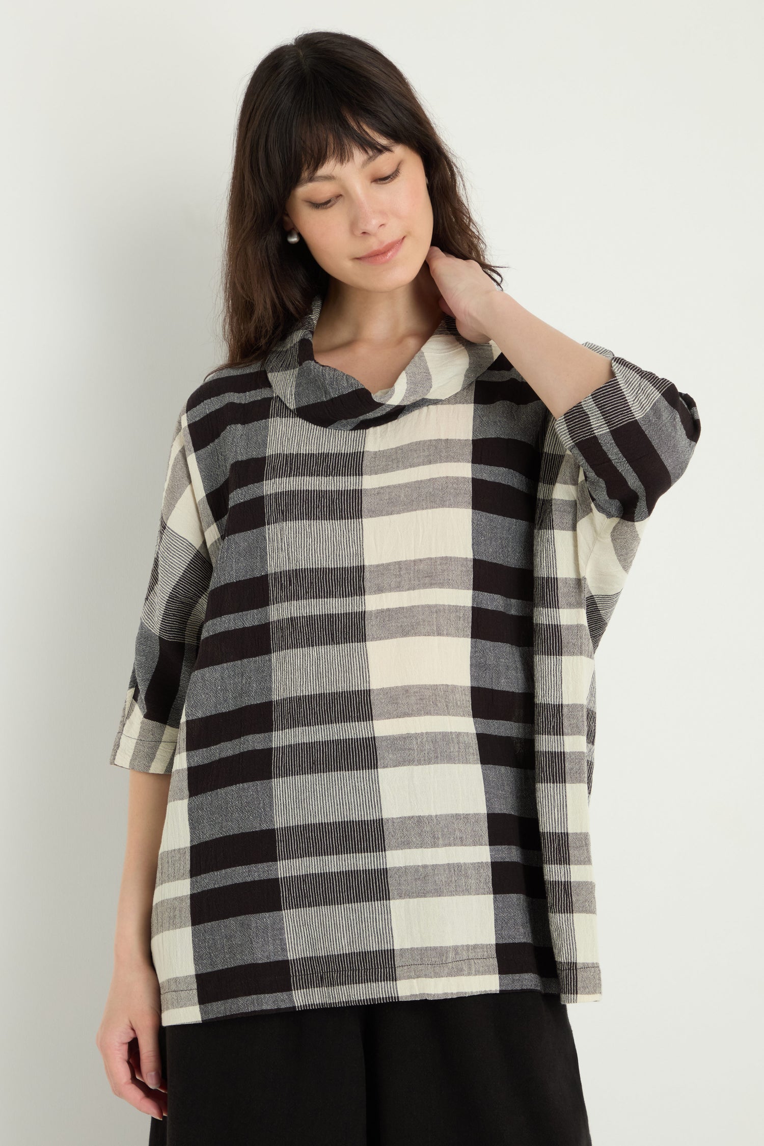 A woman wears the Monochrome Crinkle Check Cowl Neck Top with three-quarter sleeves, standing against a plain light background.