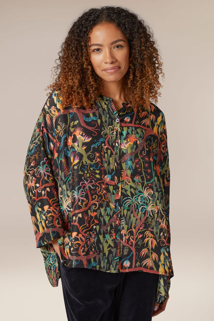 A woman wearing a Faraway Jungle Silk Boxy Shirt with a floral print.