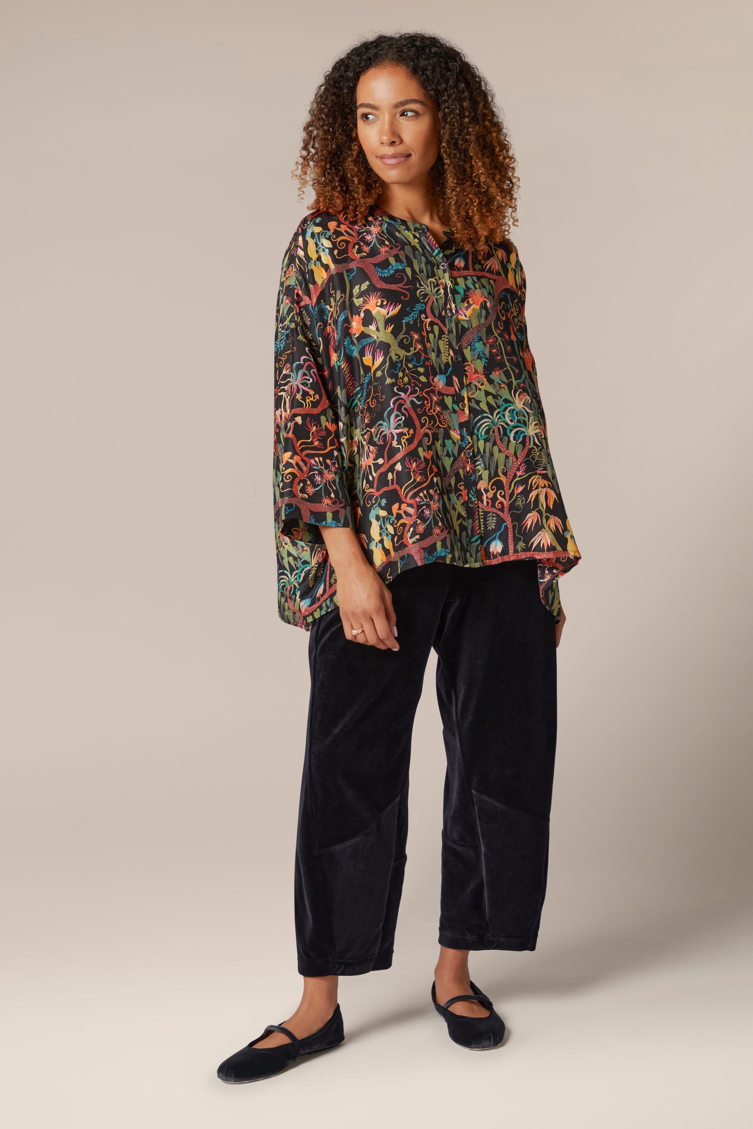 A woman wearing a Faraway Jungle Silk Boxy Shirt with a floral print.