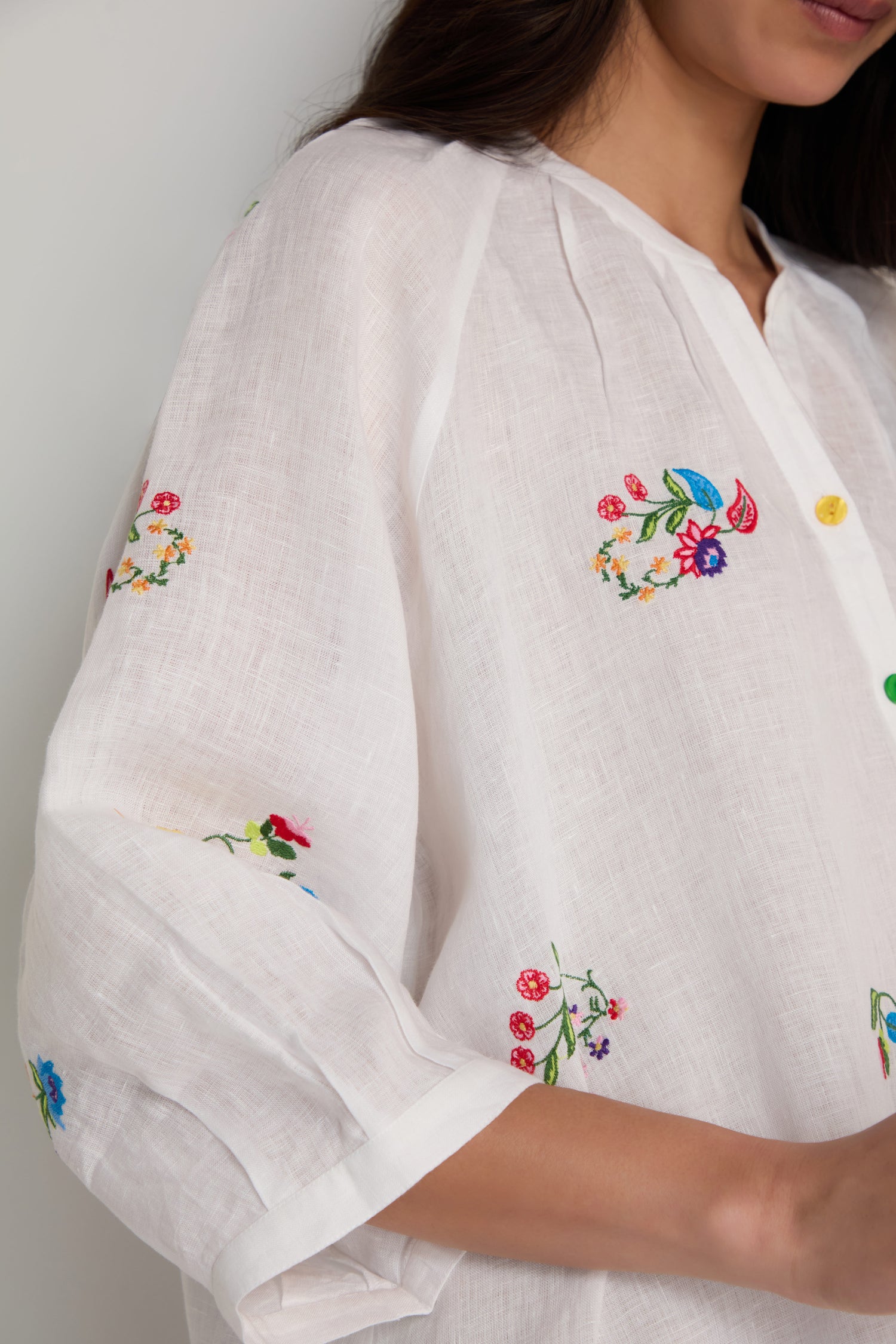 A woman wearing the Vintage Floral Embroidered Shirt, an airy linen blouse featuring vibrant floral embroidery and a button-up front.