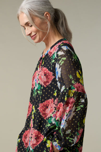 A woman donning a Vintage Floral Bouquet Shirt adorned with a beautiful floral print.