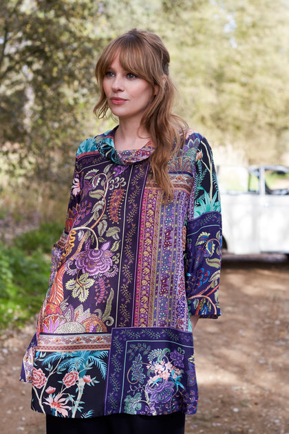 A woman in a Mythical Print Silk Tunic, standing next to a car.