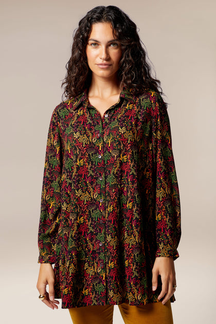 A woman wearing a long-sleeved Magical Forest Print Shirt featuring an autumnal forest motif.