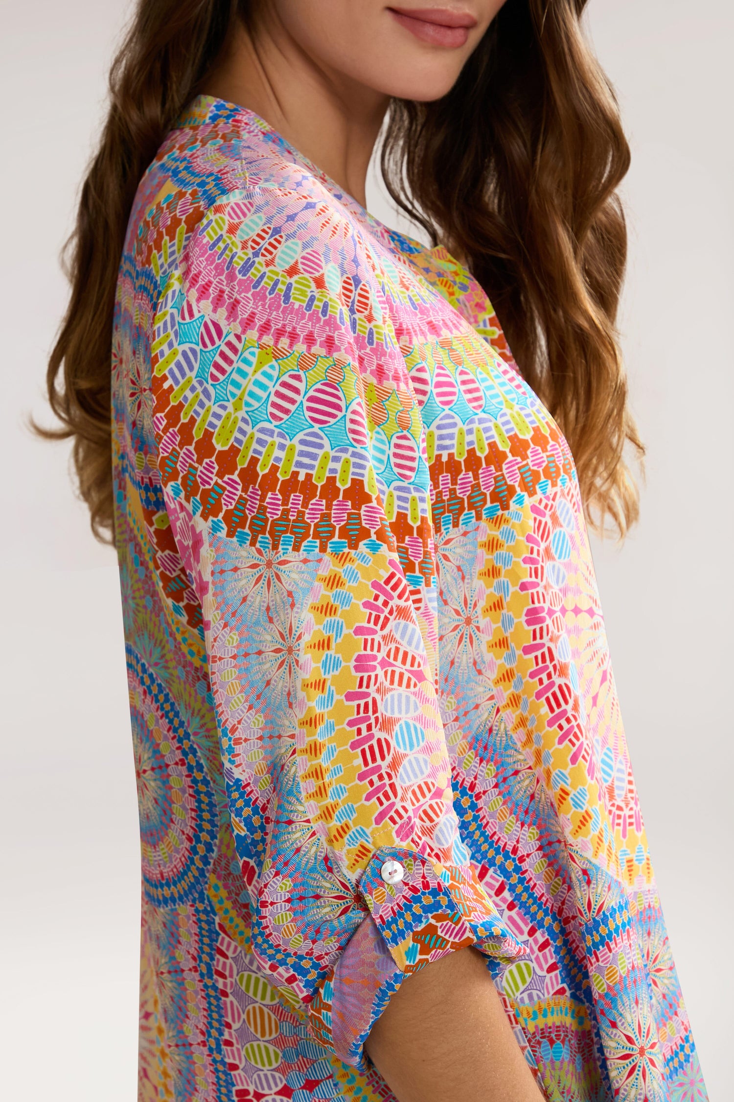 A person wearing a Circle Mandala Print Shirt with rolled-up sleeves and a band collar, standing against a plain background. The focus is on the upper body and detailed design of the pure viscose shirt.