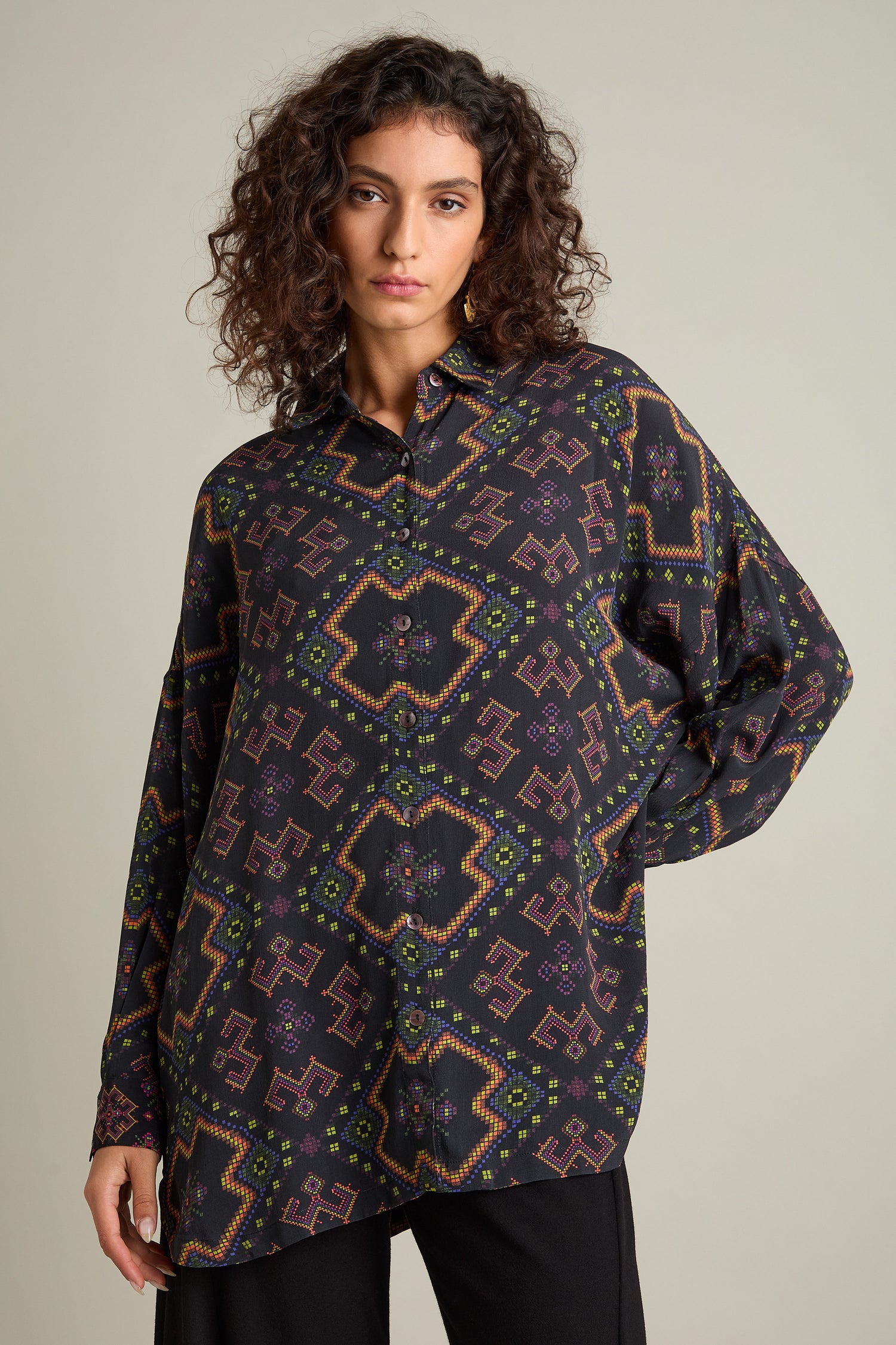 Person wearing the Pixelated Jacquard Print Shirt, which boasts a colorful geometric pattern on a neutral background and features an oversized boxy fit with long sleeves.