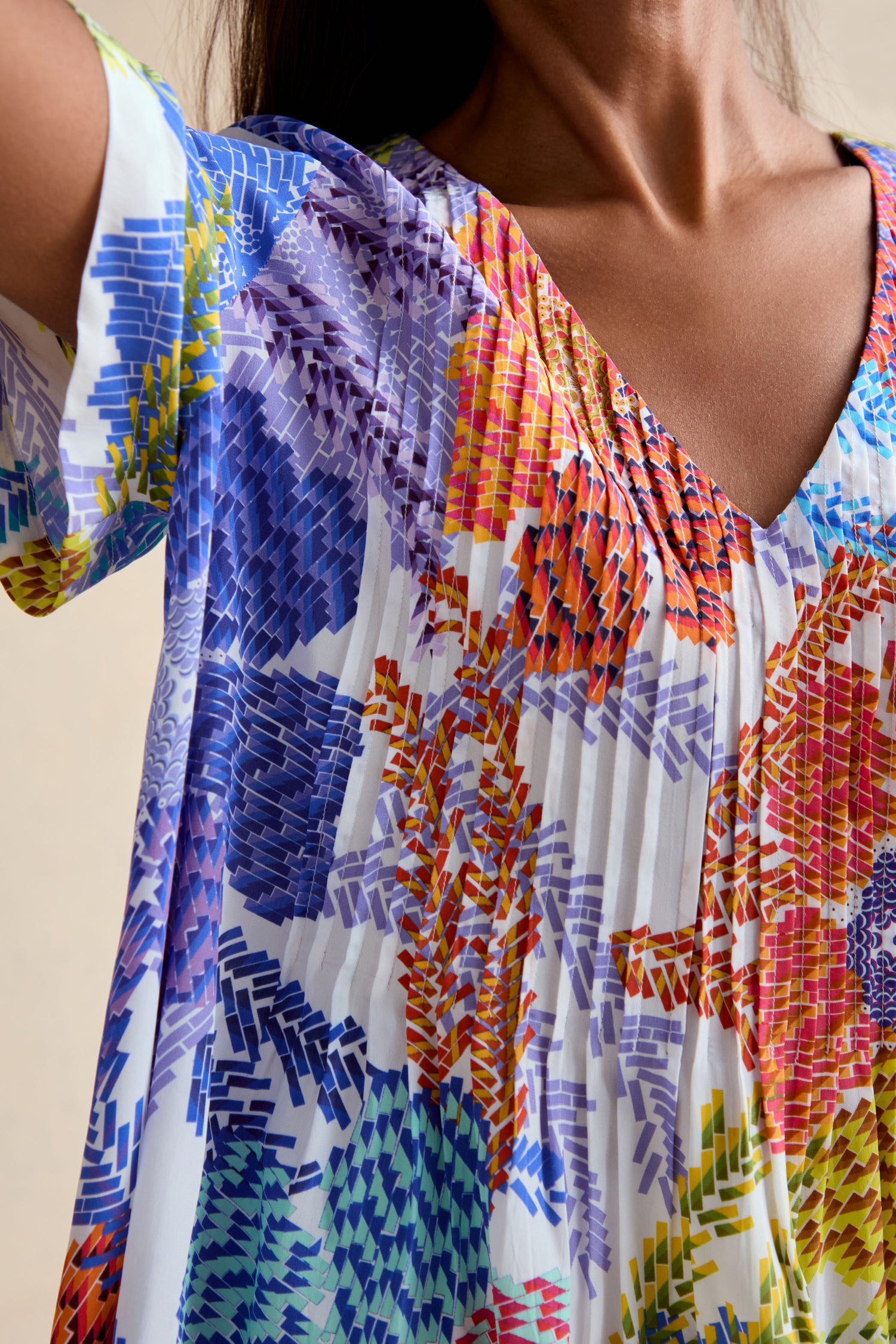 Close-up of a person wearing the Pixelated Petals Print Top, featuring short sleeves, a colorful geometric floral pattern, relaxed A-line fit, and a flattering V-neckline.