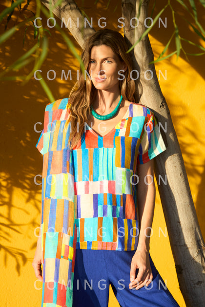 A woman in a Painted Stripes Linen Top and blue pants stands by a yellow wall and tree, with "COMING SOON" and the code GRT6917-VPS overlaid multiple times.