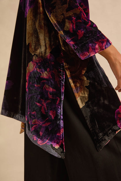 Midnight Peonies velvet tunic with a purple and black floral print and side slits worn over black trousers.