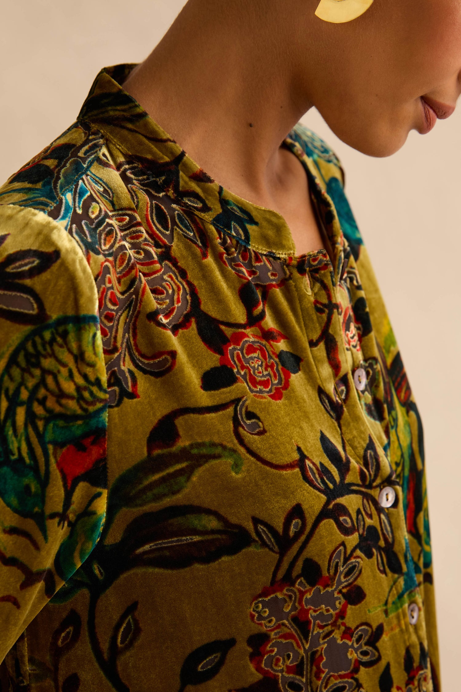 A person wears a Silk Velvet Floral Devore Shirt, a button-down featuring a green floral silk devoré pattern.