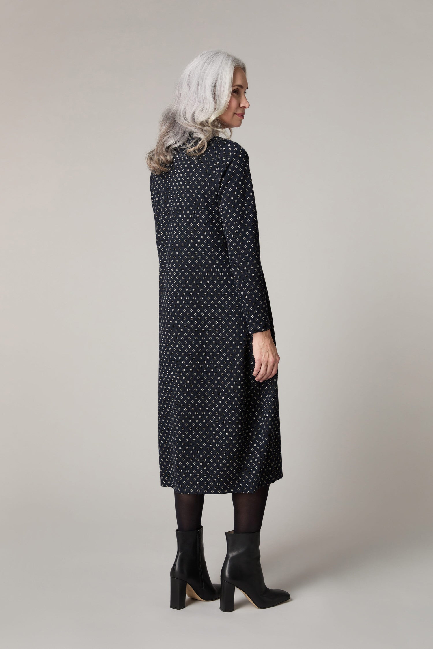 The back view of a woman wearing a black polka dot Lurex Spot Jersey Dress.