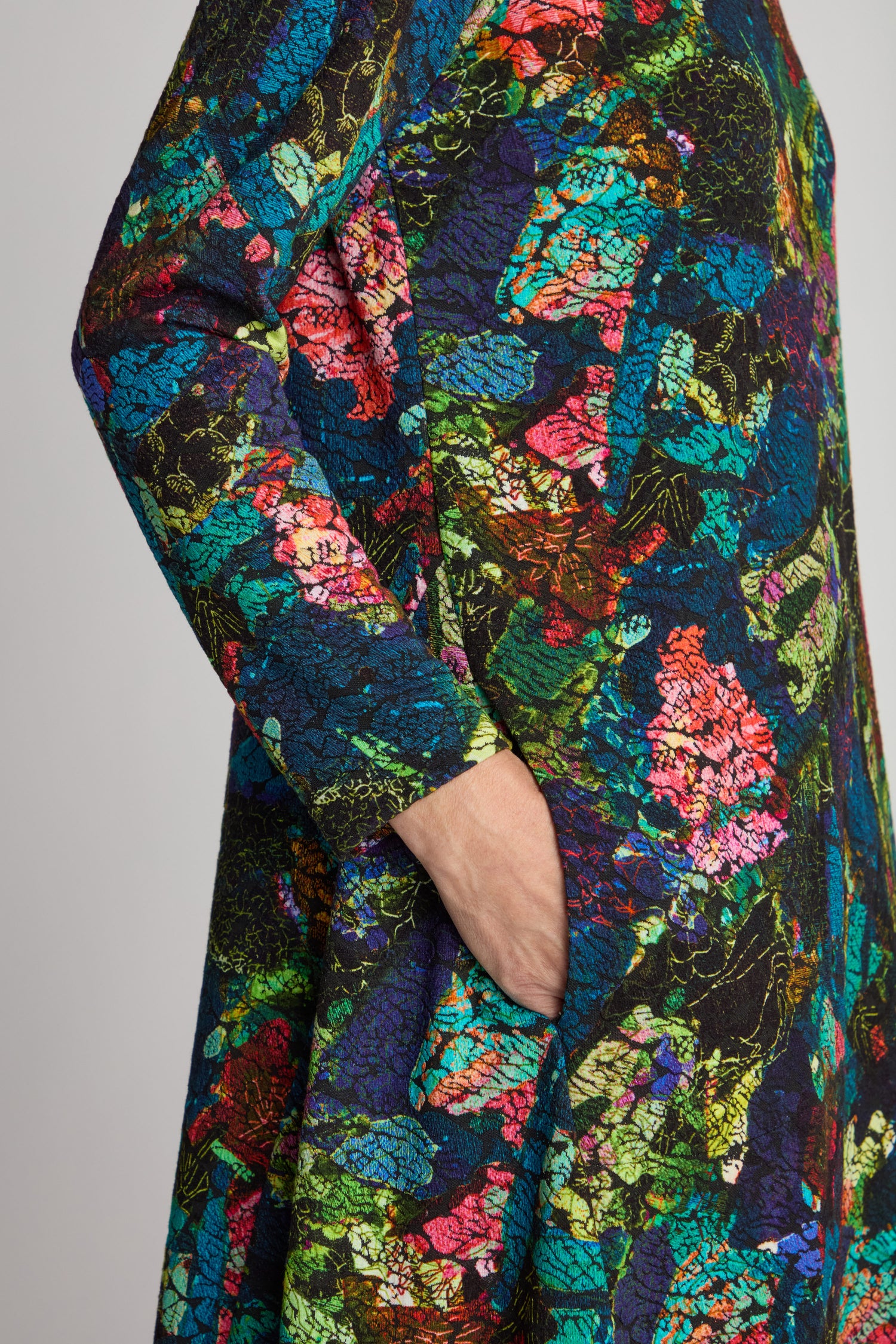 Close-up of a person wearing an Abstract Floral Jersey Bubble Dress with one hand partially in a side pocket.