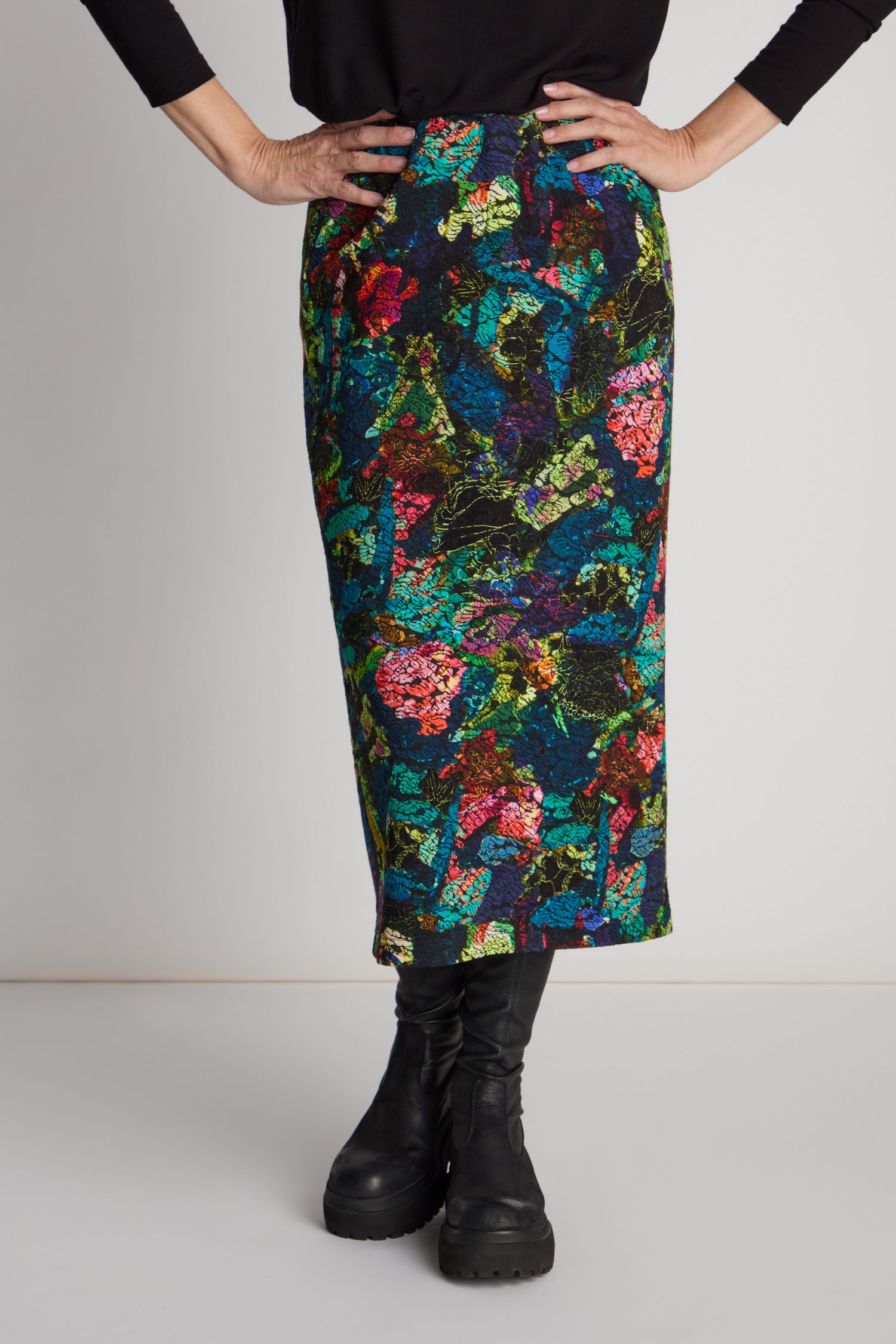 Person wearing an Abstract Floral Jersey Tube Skirt with an elasticated waistband and black boots, hands confidently on hips against a plain background.