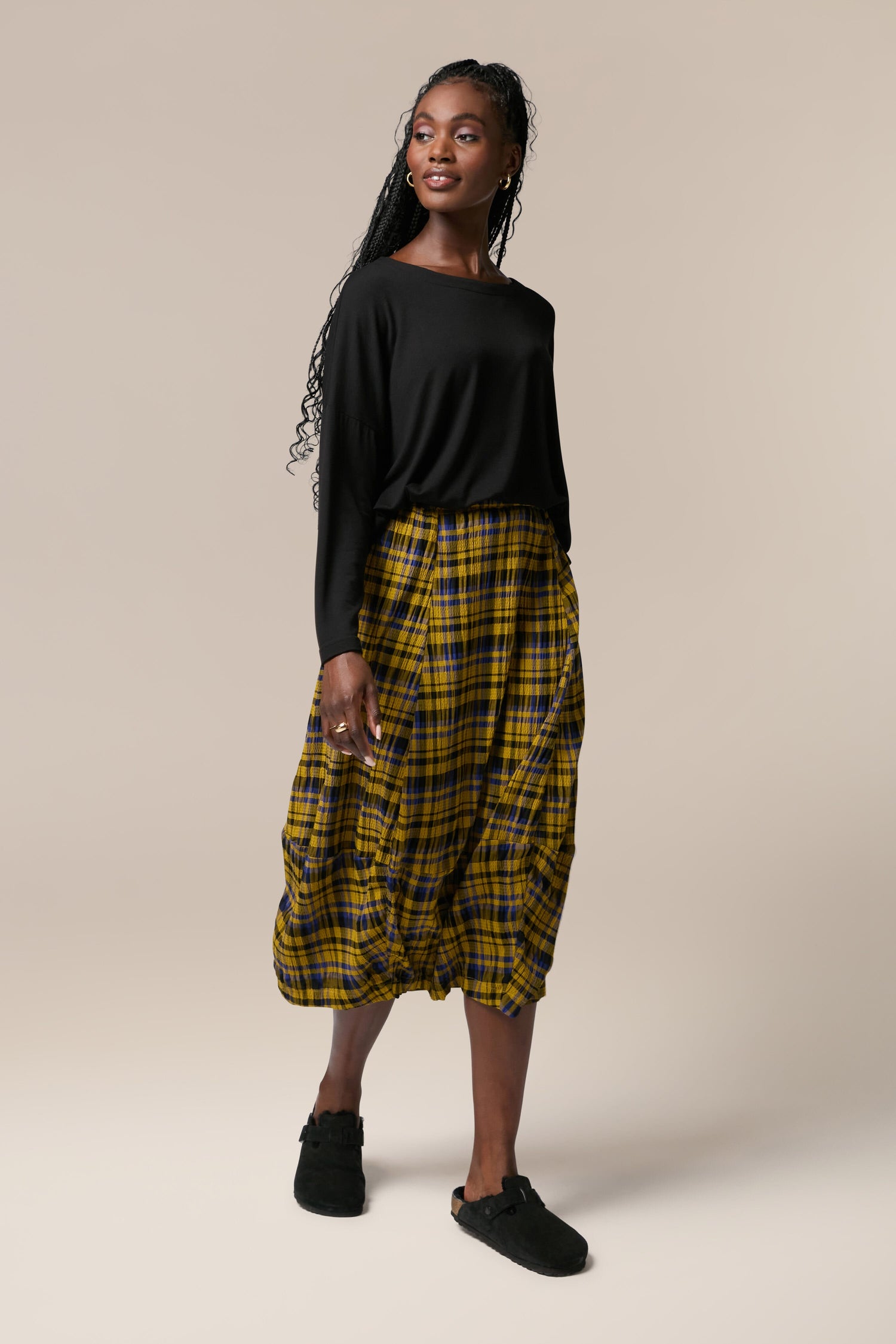 A woman wearing a yellow and black Crinkle Check Skirt with an elasticated waist.