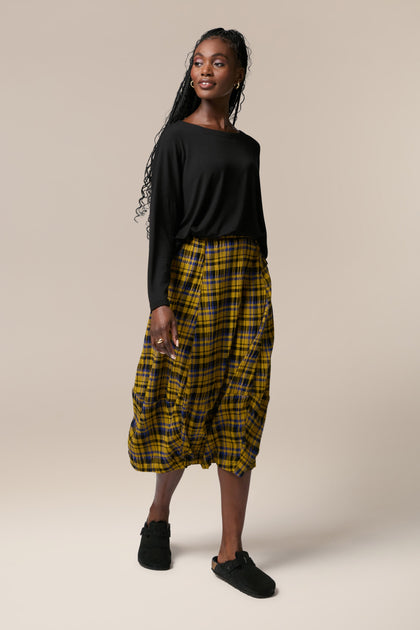 A woman wearing a yellow and black Crinkle Check Skirt with an elasticated waist.