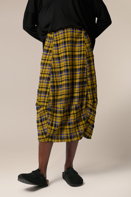A woman wearing a Crinkle Check Skirt with a yellow and black check pattern.